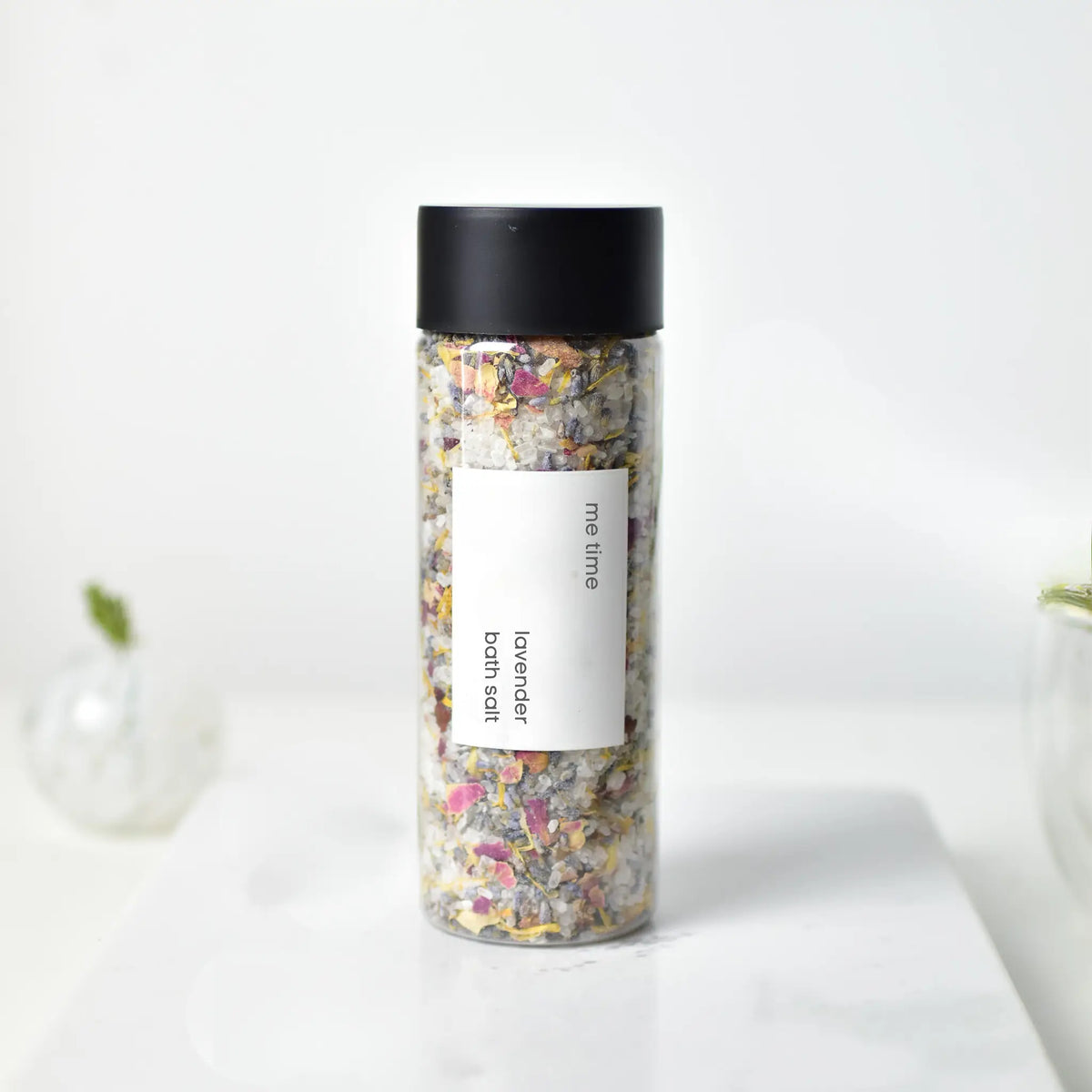Bottle of bath salts with a black lid on a white background