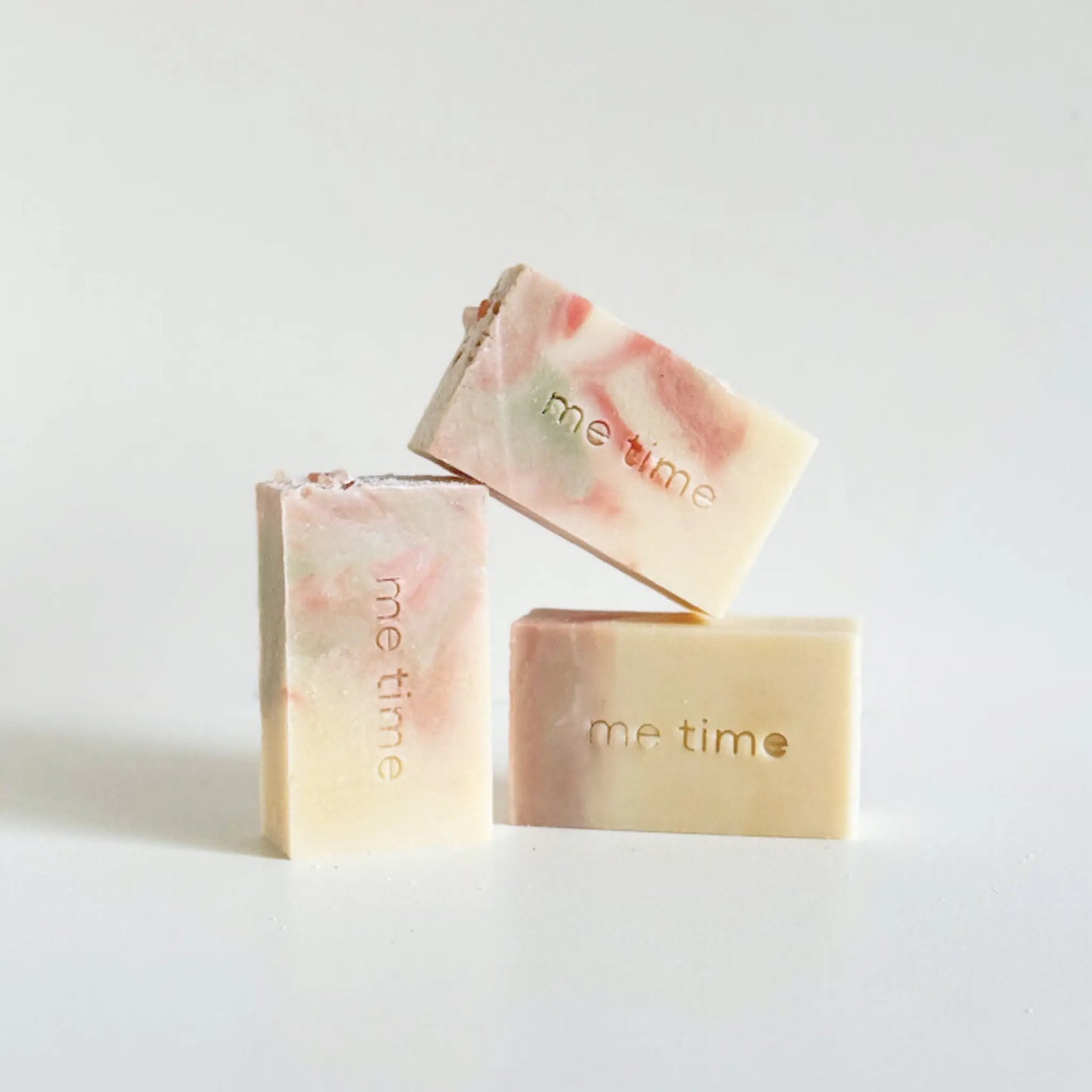 Lavender handmade soap bar with soft floral tones, colored with pink and green clay, photographed on a calm neutral background.
