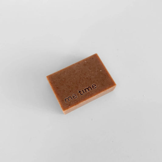 Handmade coffee and vanilla soap bar with visible coffee grounds and warm brown tones, styled in a calm spa setting