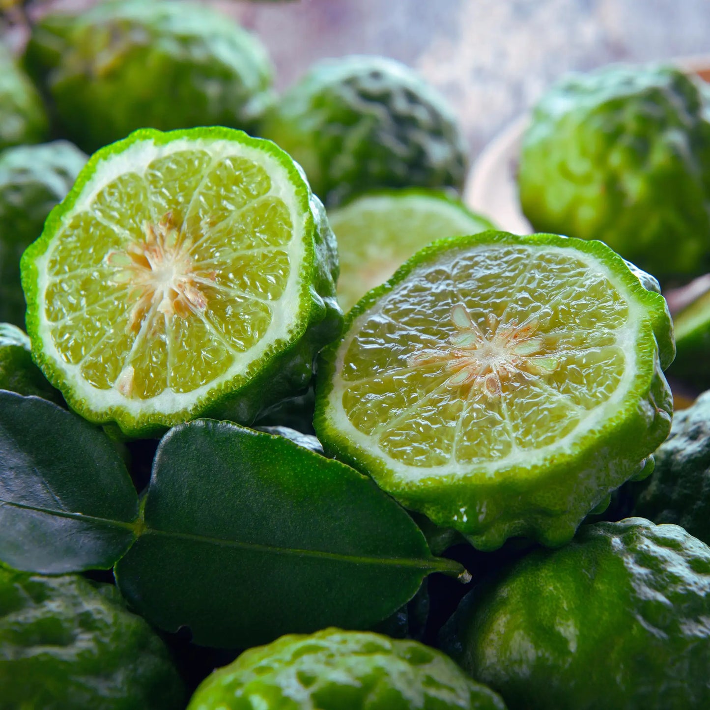 Green citrus fruit, possibly bergamot, with a close-up of a halved fruit showing its juicy interior.