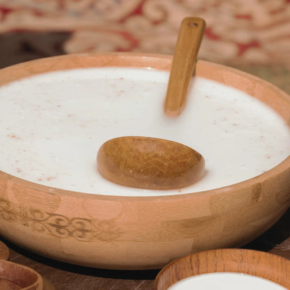Wooden bowl with a wooden spoon and Camel Milk on a patterned fabric background