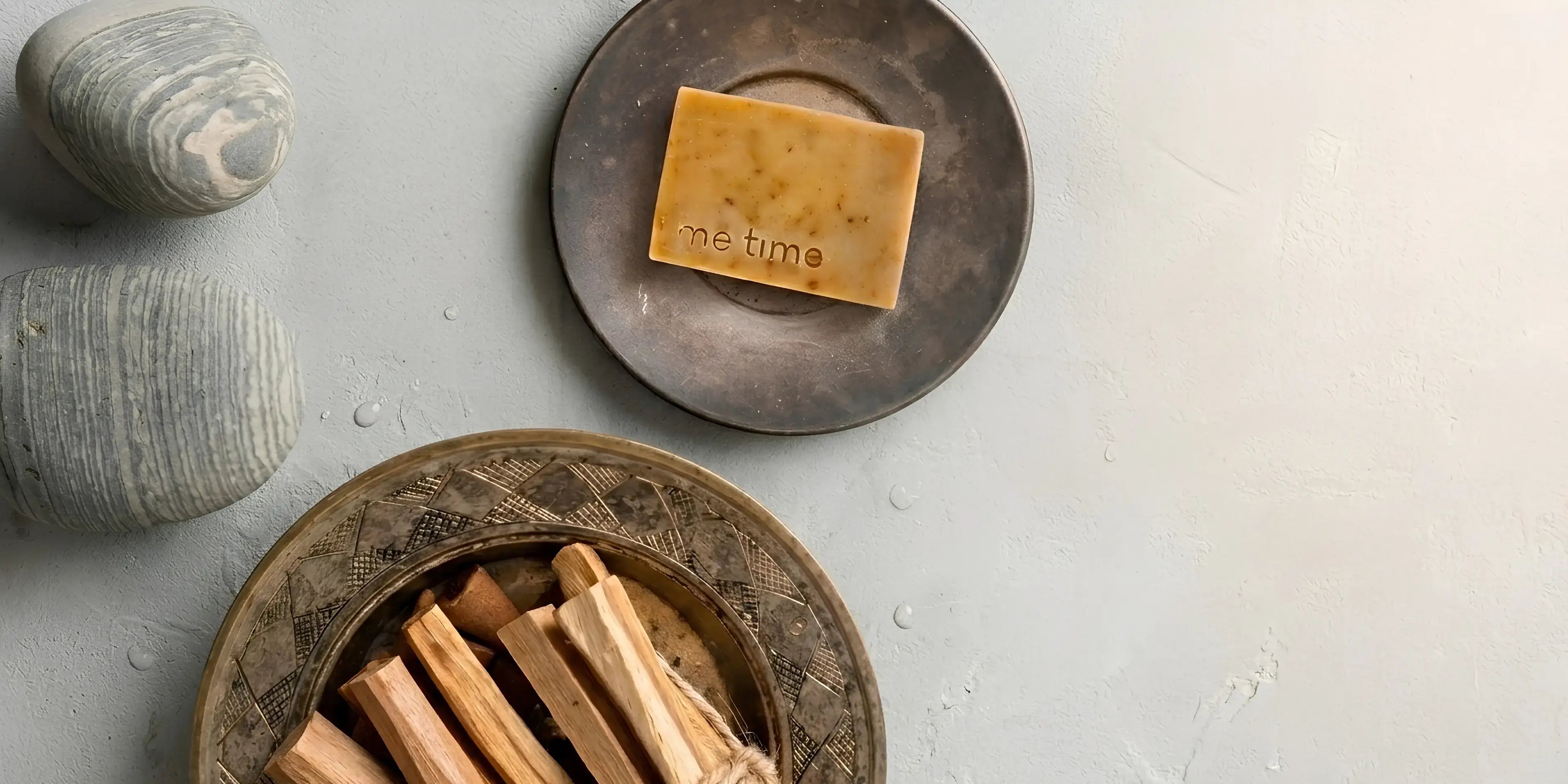 Bar of soap with 'the time' branding on a stone surface with sandalwood wooden sticks.