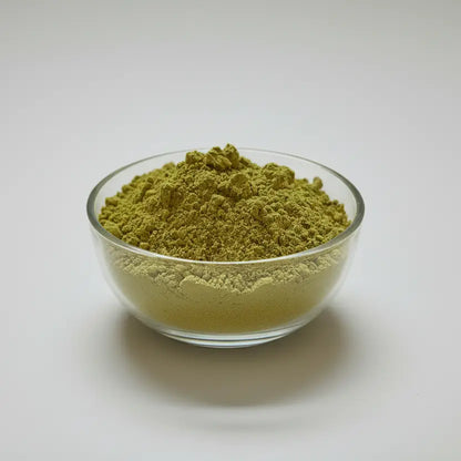 Glass bowl filled with green powder on a white background