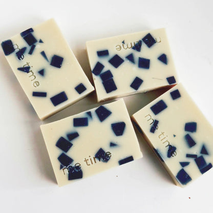 Four soap bars with blue and black square patterns on a white background