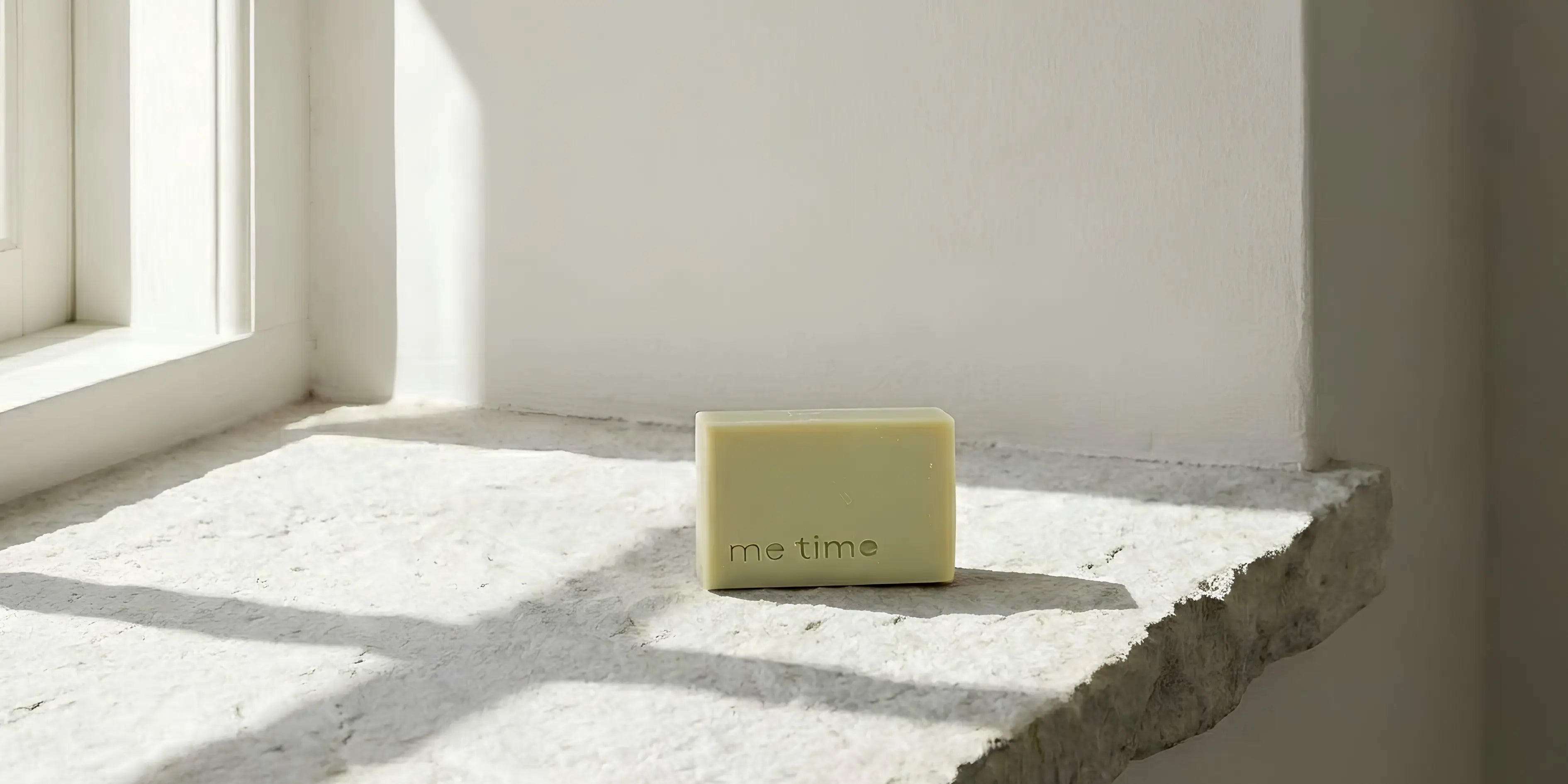 Bar of soap labeled 'me time' on a stone surface with sunlight casting shadows.