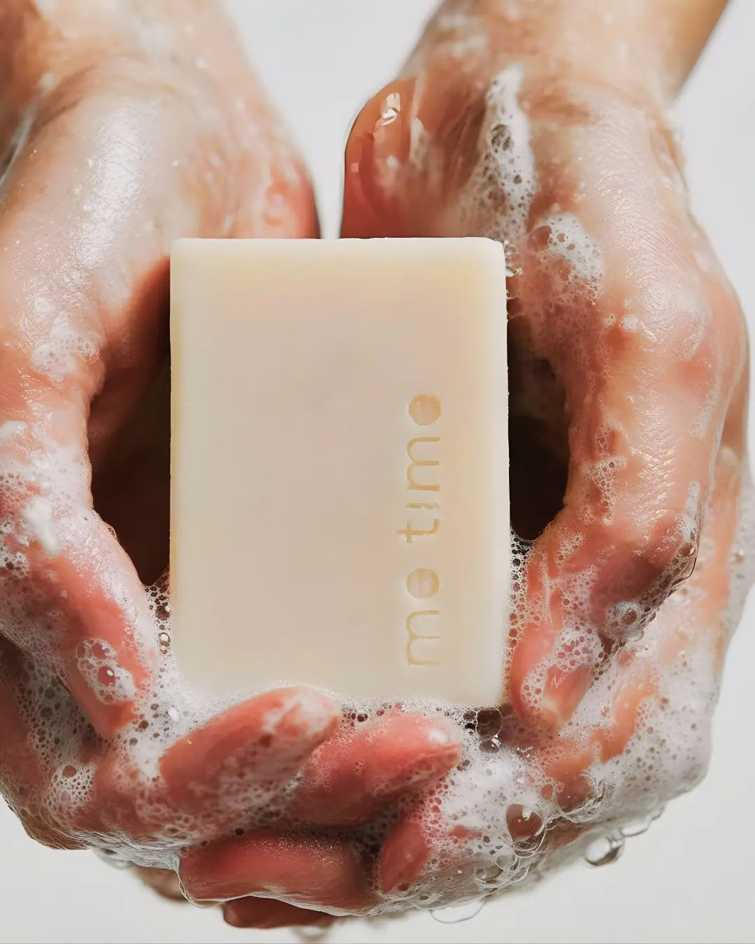 Hands holding me time soap bar with on a white background
