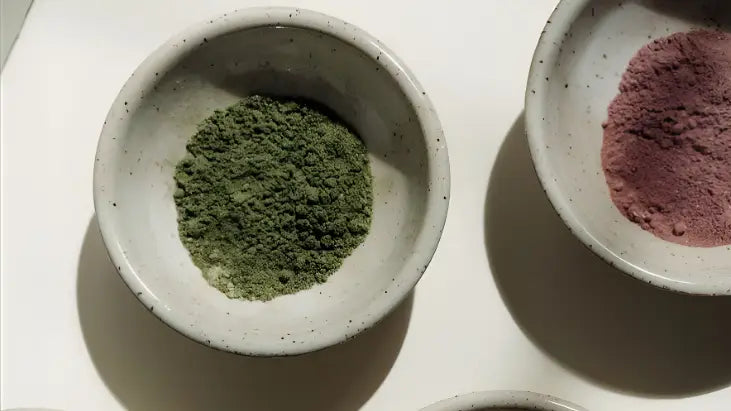 Two bowls with green and red powders on a white surface, UAE