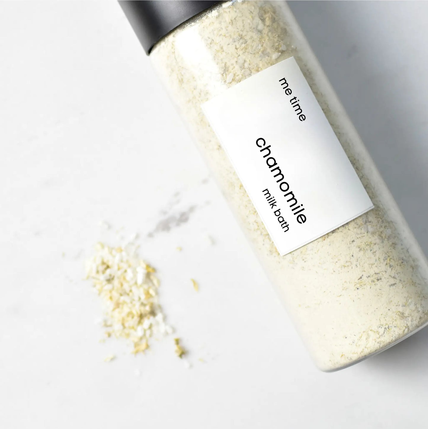 Bottle of chamomile milk bath with a label on a light background