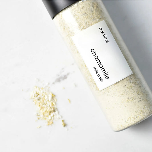 Bottle of chamomile milk bath with a label on a light background