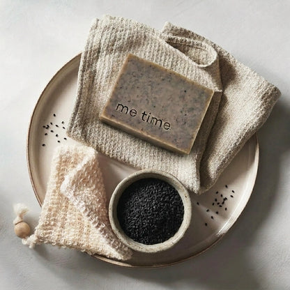 me time black seed soap on a towel, next to a bowl of black seeds on a plate.