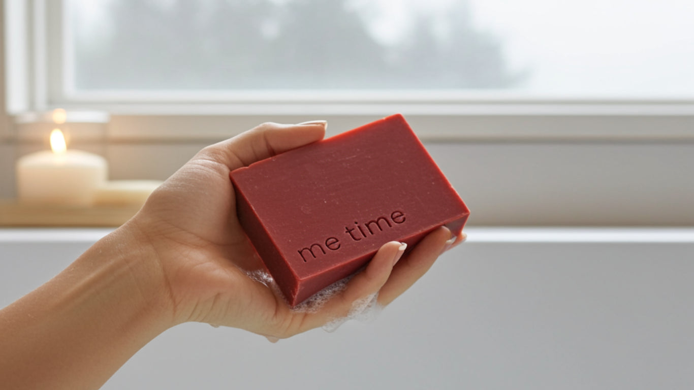 Hand holding a red bar of soap with 'me time' text, blurred background