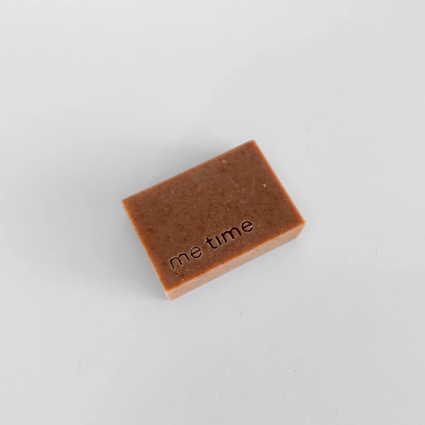 Handmade coffee and vanilla soap bar with visible coffee grounds and warm brown tones, styled in a calm spa setting