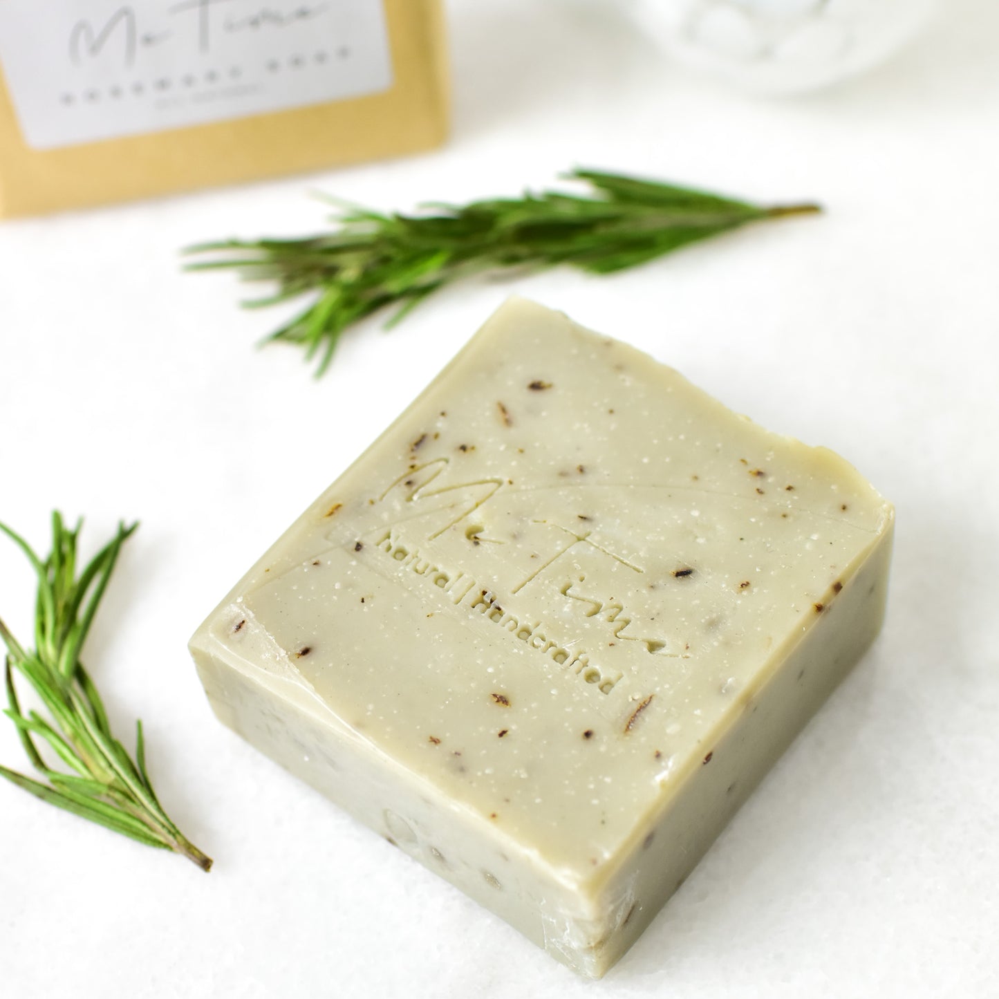 Handmade natural artisan soap bar with rosemary and clay, featuring gentle exfoliation and deep hydration properties. The soap is crafted with olive oil, coconut oil, sunflower oil, and shea butter, and is scented with rosemary essential oil. It includes white, green, and grey clay for purifying and rejuvenating the skin.